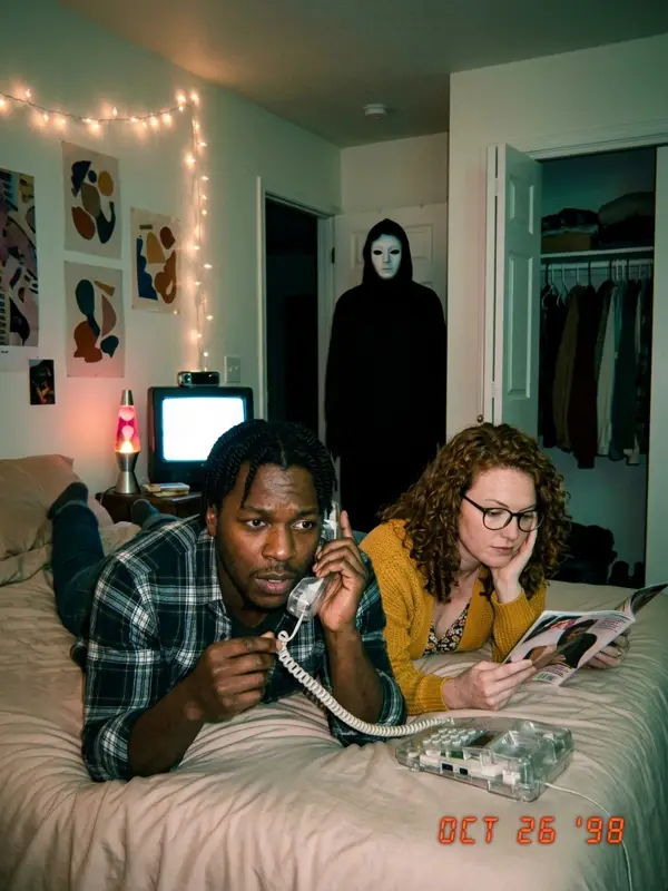 Couple on a bed with a corded phone, masked figure in the closet doorway